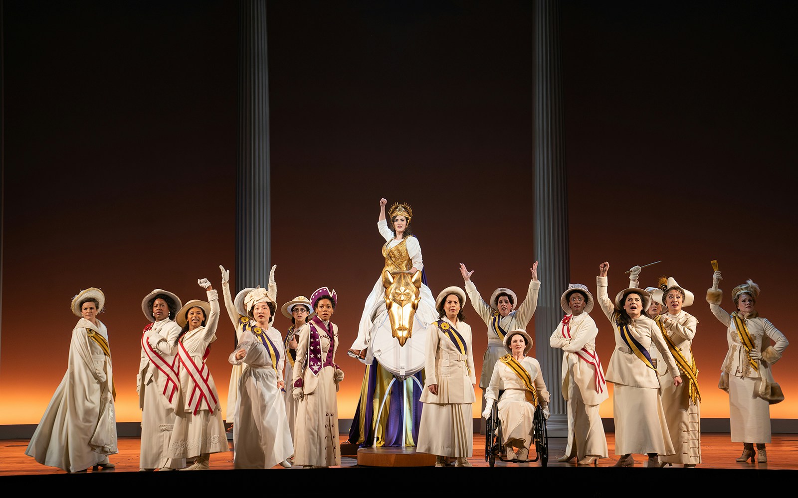 Performers in period costumes on stage during the show "Suffs" with a central figure on a horse.