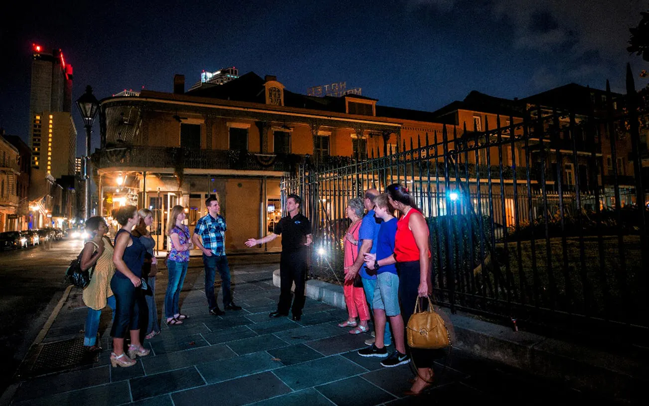 Group on New Orleans ghost tour at night near historic building.