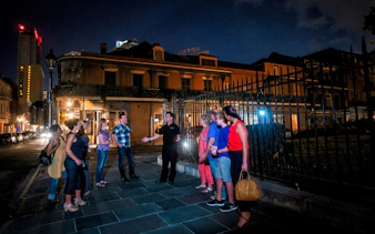 Group on New Orleans ghost tour at night near historic building.