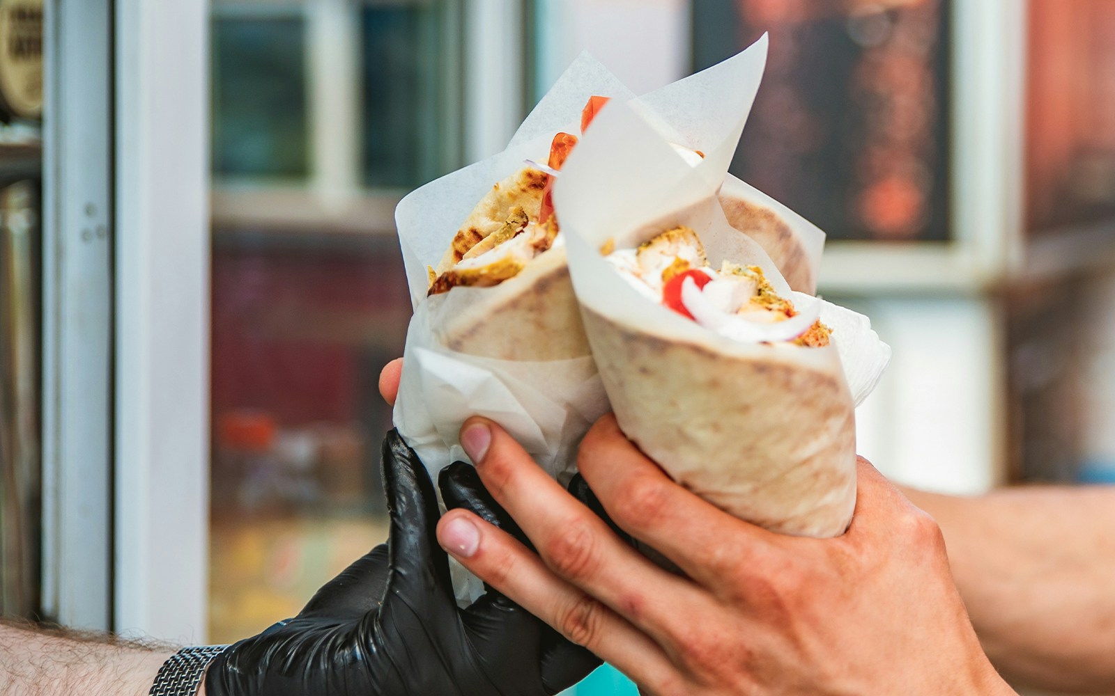 Shawarma wrapped in pita bread with fresh vegetables and sauce.