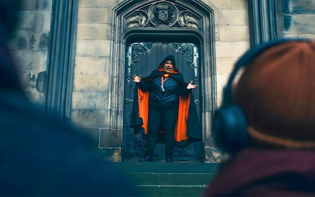 Guide in cloak leading guests on Edinburgh Hidden Haunted Tour.