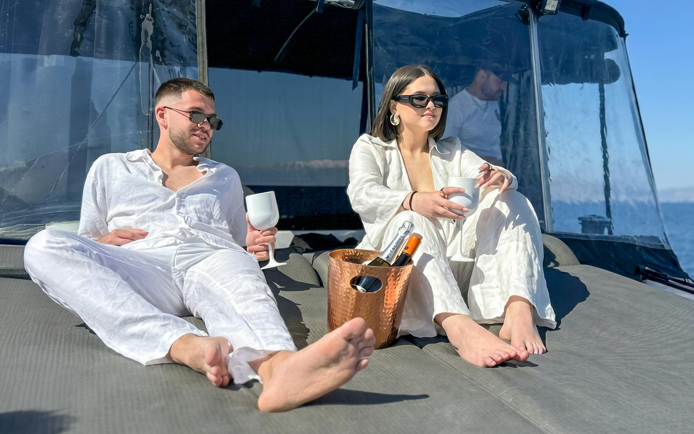 Couple relaxing on Heraklion catamaran with drinks, enjoying all-inclusive cruise experience.