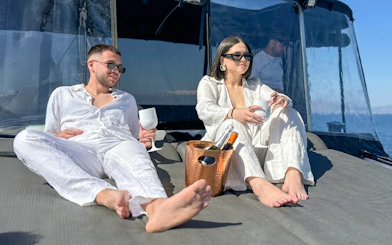 Couple relaxing on Heraklion catamaran with drinks, enjoying all-inclusive cruise experience.
