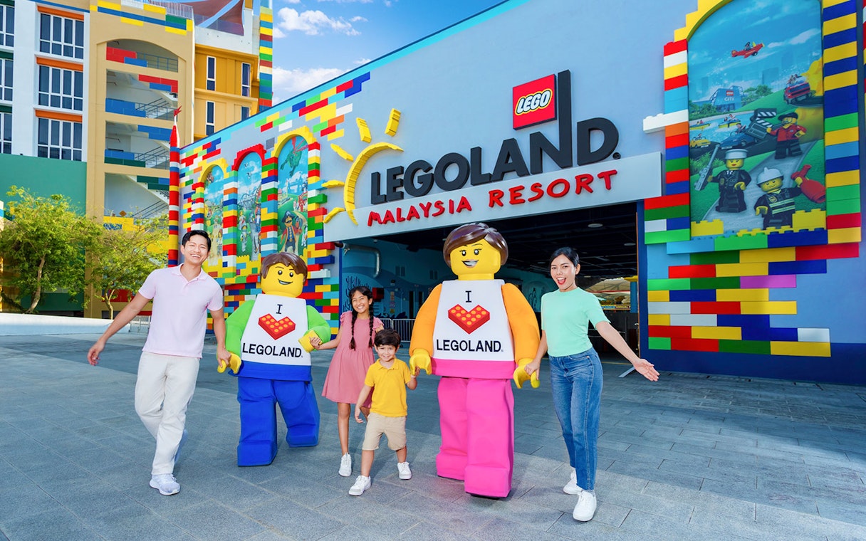 Family with LEGO characters at Legoland Malaysia Resort entrance.