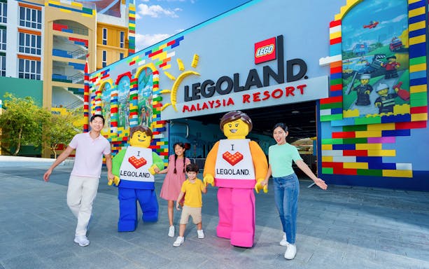 Family with LEGO characters at Legoland Malaysia Resort entrance.