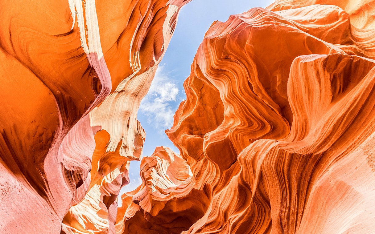 Lower Antelope Canyon's swirling sandstone formations under a clear blue sky.