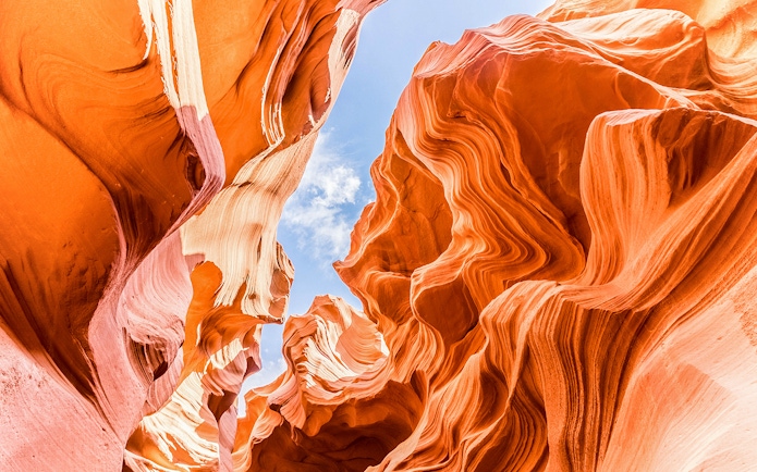 Lower Antelope Canyon's swirling sandstone formations under a clear blue sky.