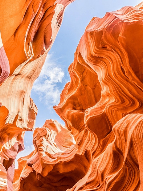 Lower Antelope Canyon's swirling sandstone formations under a clear blue sky.