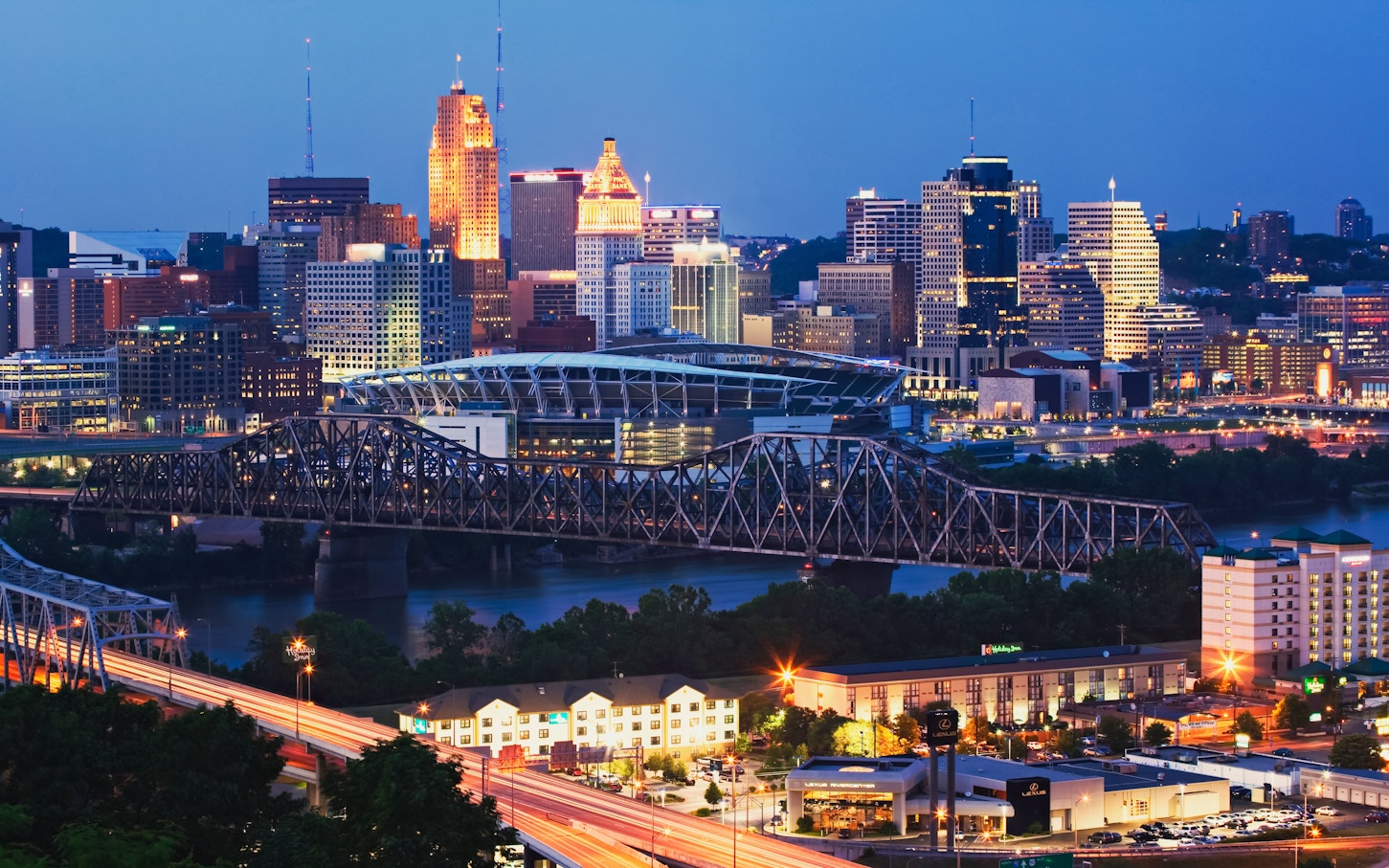 Cincinnati, Ohio skyline with illuminated buildings and bridge at dusk.