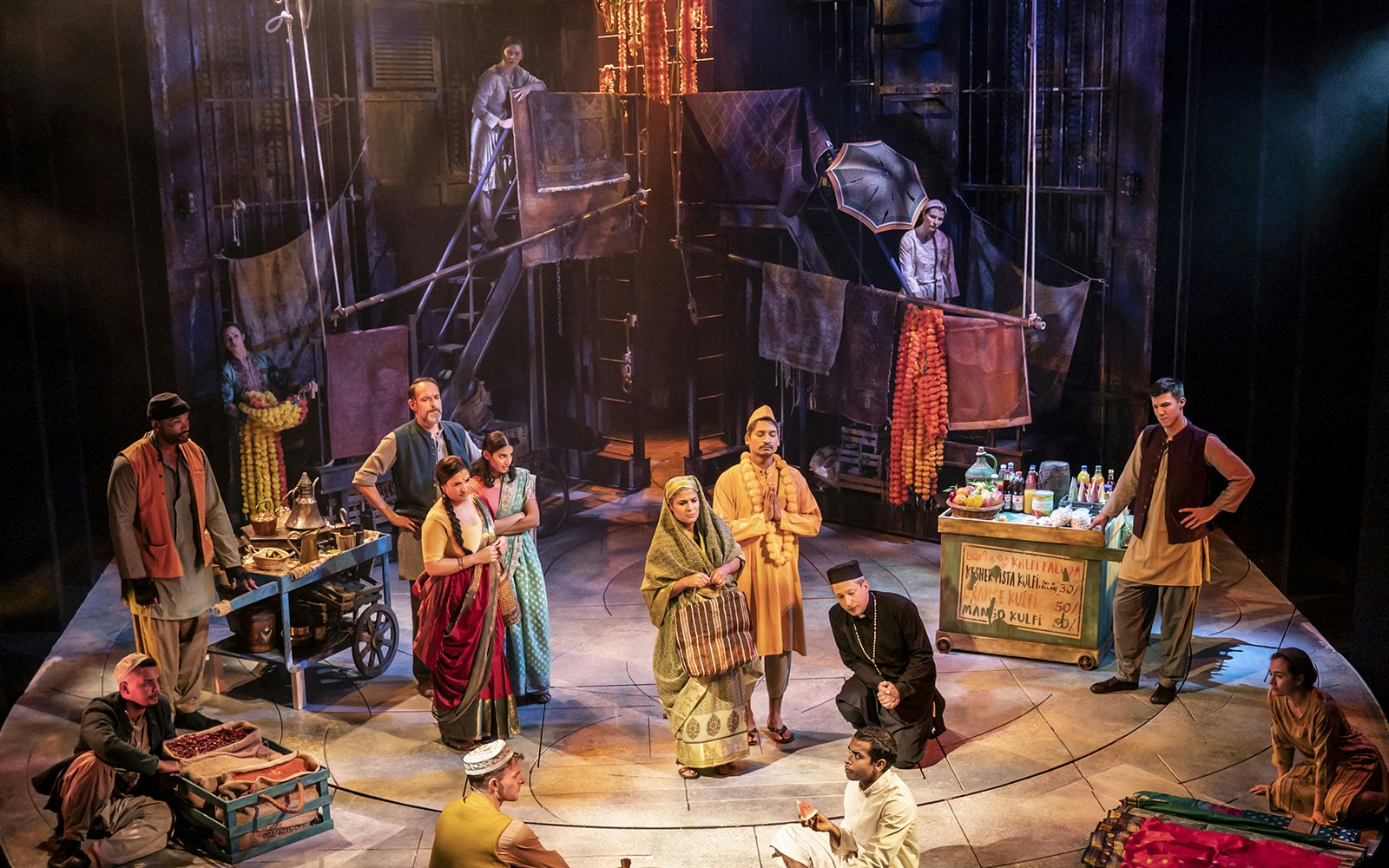Stage performance of "Life of Pi" with actors in traditional attire and market scene.