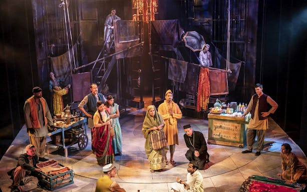 Stage performance of "Life of Pi" with actors in traditional attire and market scene.