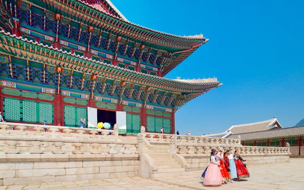 Gyeongbokgung Palace with visitors in traditional hanbok during a morning tour in Seoul.