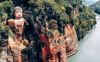 Leshan Giant Buddha carved into cliffside by river in Chengdu, China.