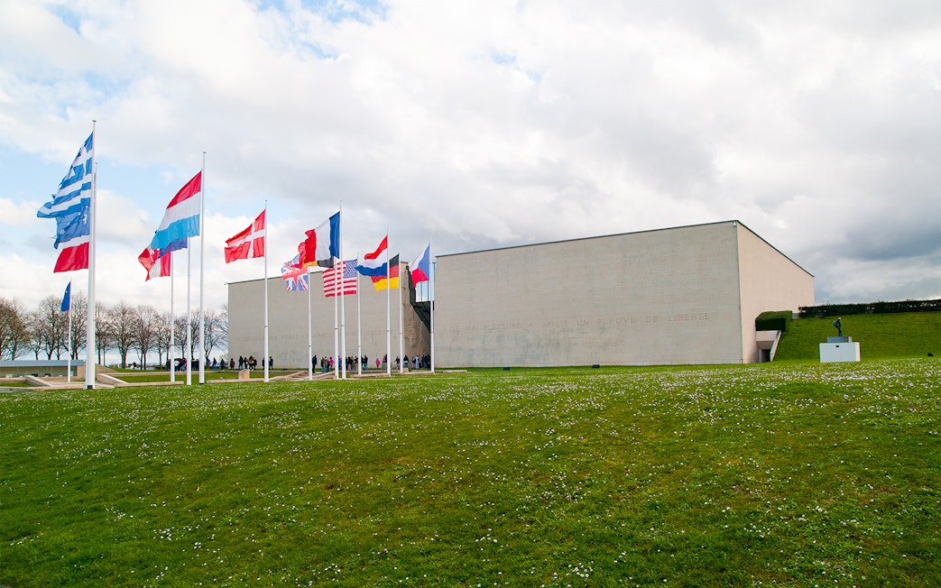 Flags outside the Caen Memorial Museum in France, with visitors entering.