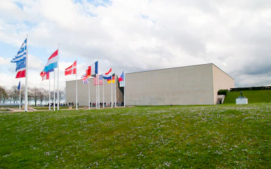Flags outside the Caen Memorial Museum in France, with visitors entering.