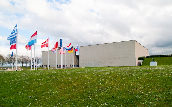Flags outside the Caen Memorial Museum in France, with visitors entering.