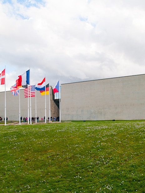 Flags outside the Caen Memorial Museum in France, with visitors entering.
