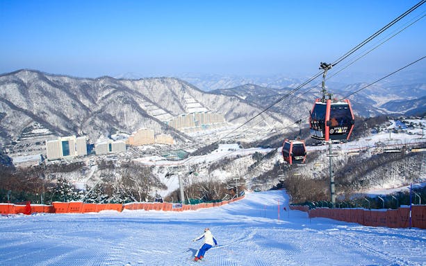 Ski slope and cable cars at Vivaldi Park Ski World, mountains in background, South Korea.
