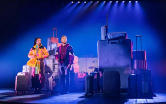 Two actors on stage with suitcases in "Two Strangers (Carry a Cake Across New York)" Broadway show.