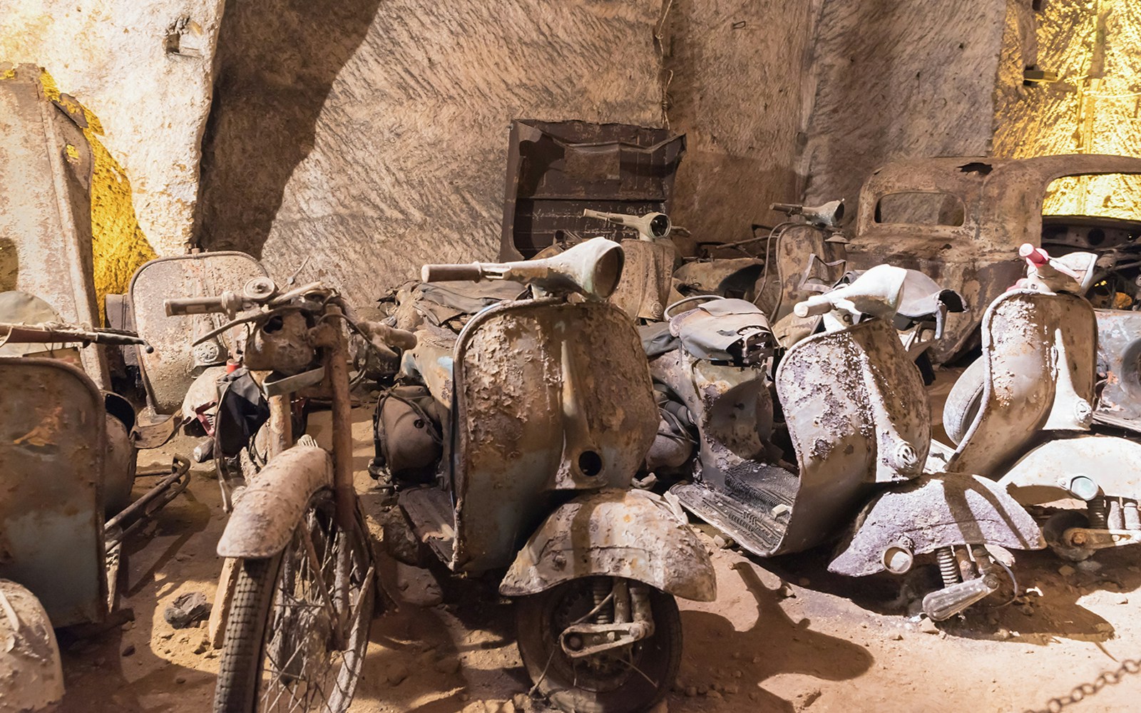 Naples Underground tour showcasing abandoned vehicles in historic tunnels.