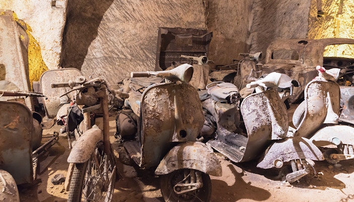 Naples Underground tour showcasing abandoned vehicles in historic tunnels.