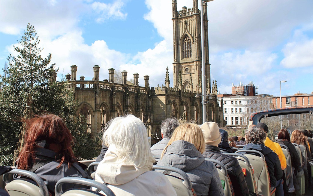 Passengers on open-top bus tour passing St. Luke's Church, Liverpool.