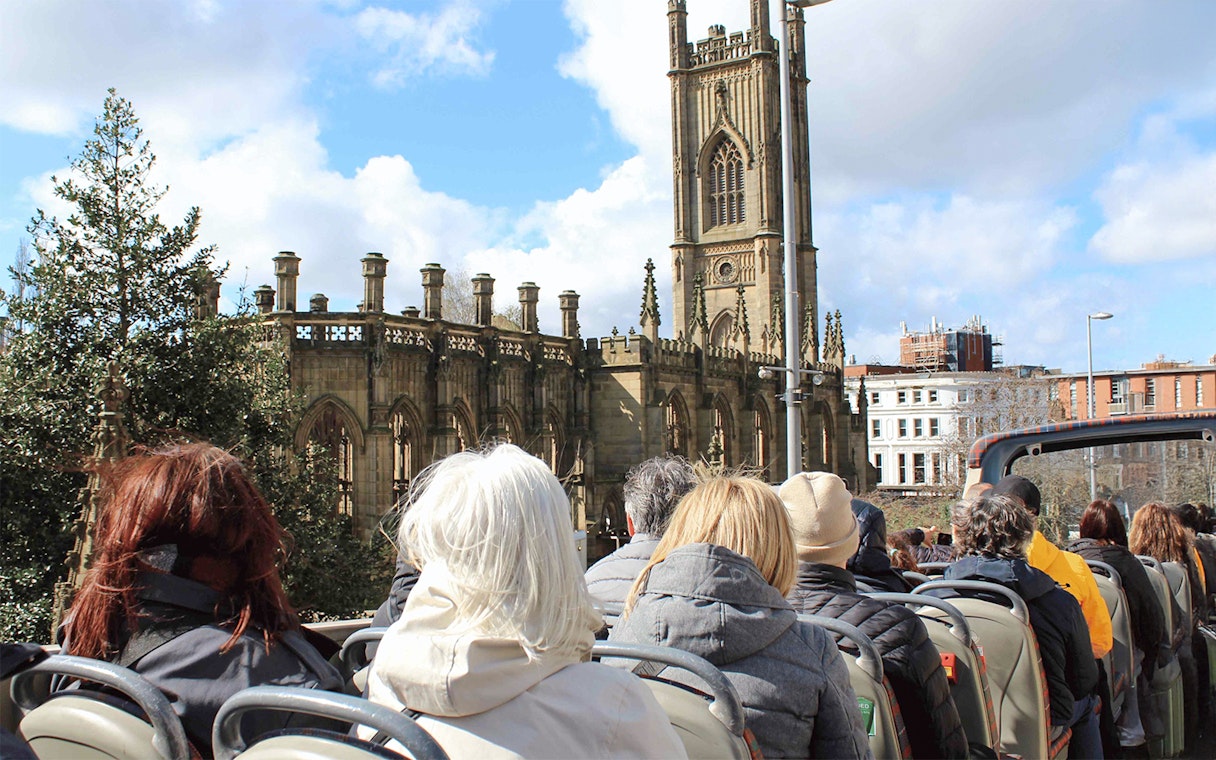 Passengers on open-top bus tour passing St. Luke's Church, Liverpool.