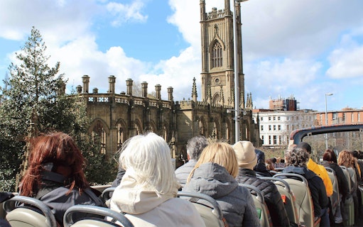 Passengers on open-top bus tour passing St. Luke's Church, Liverpool.