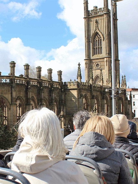 Passengers on open-top bus tour passing St. Luke's Church, Liverpool.