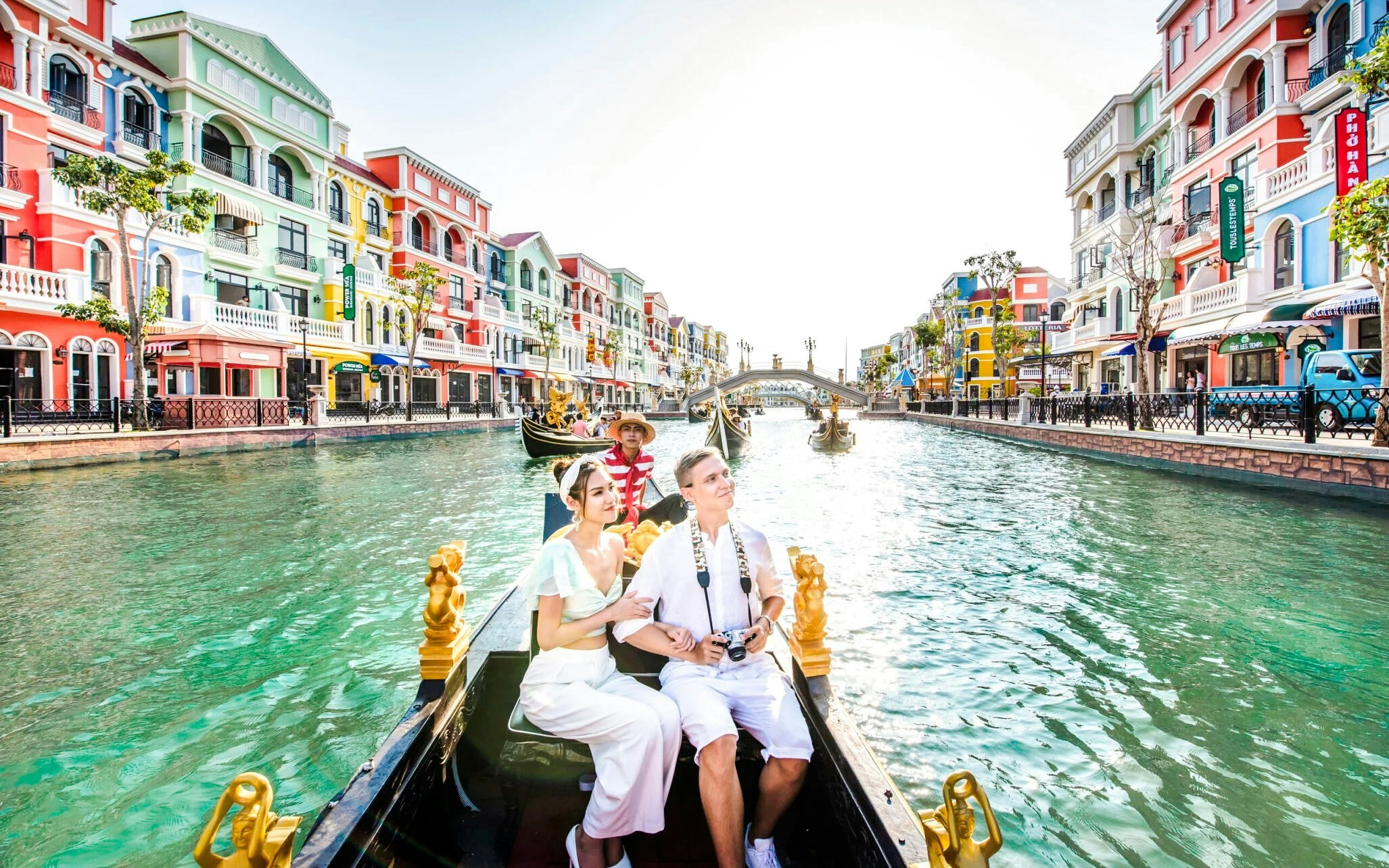 Couple enjoying a gondola ride on a canal in Venice with colorful buildings.