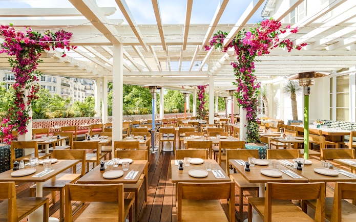 Brasserie Auteuil interior with wooden tables, chairs, and floral decorations.