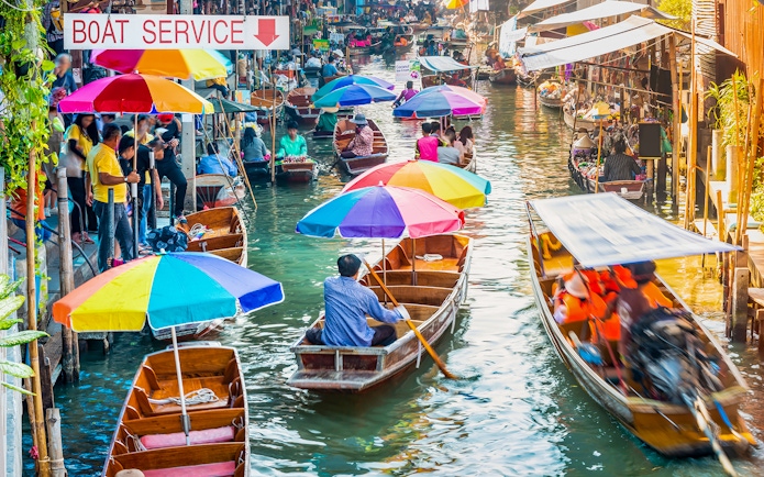 Boats with colorful umbrellas at Damnoen Saduak Floating Market, Thailand.
