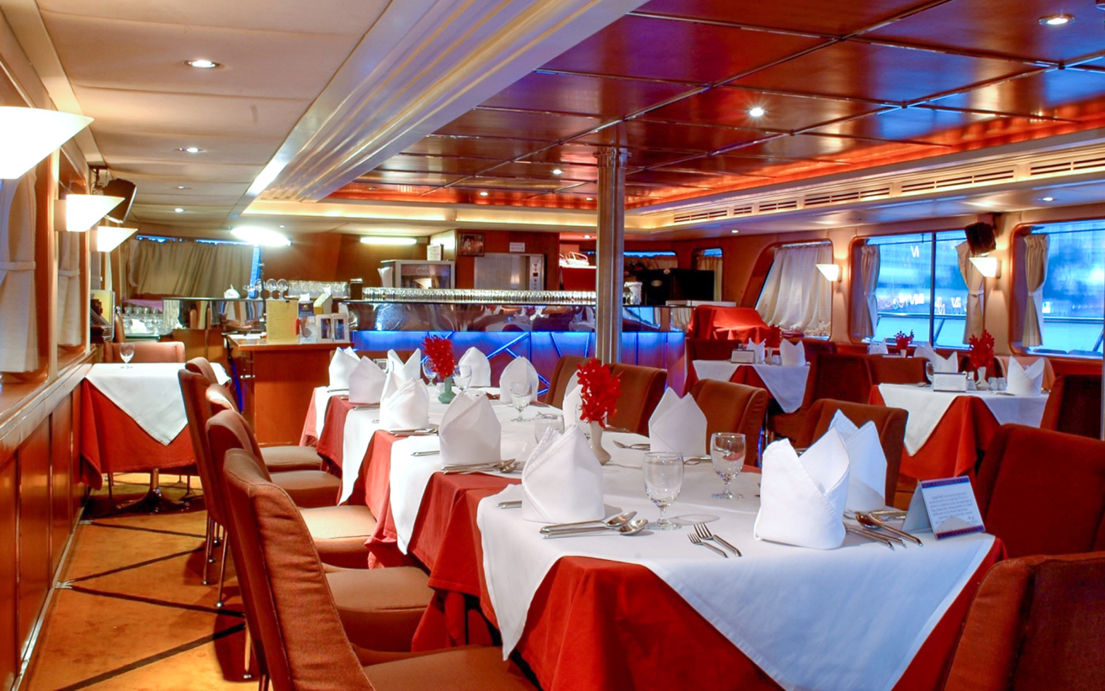 Elegant dining setup on the Grand Pearl Dinner Cruise with red and white table settings.