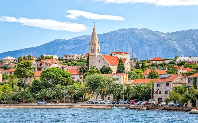 Coastal view of Bol Town with church and mountains on Brac Island, Croatia.