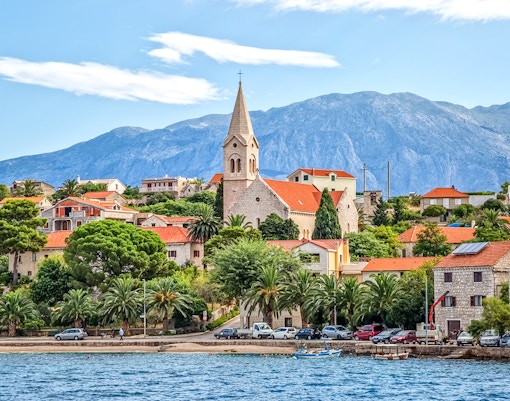 Coastal view of Bol Town with church and mountains on Brac Island, Croatia.