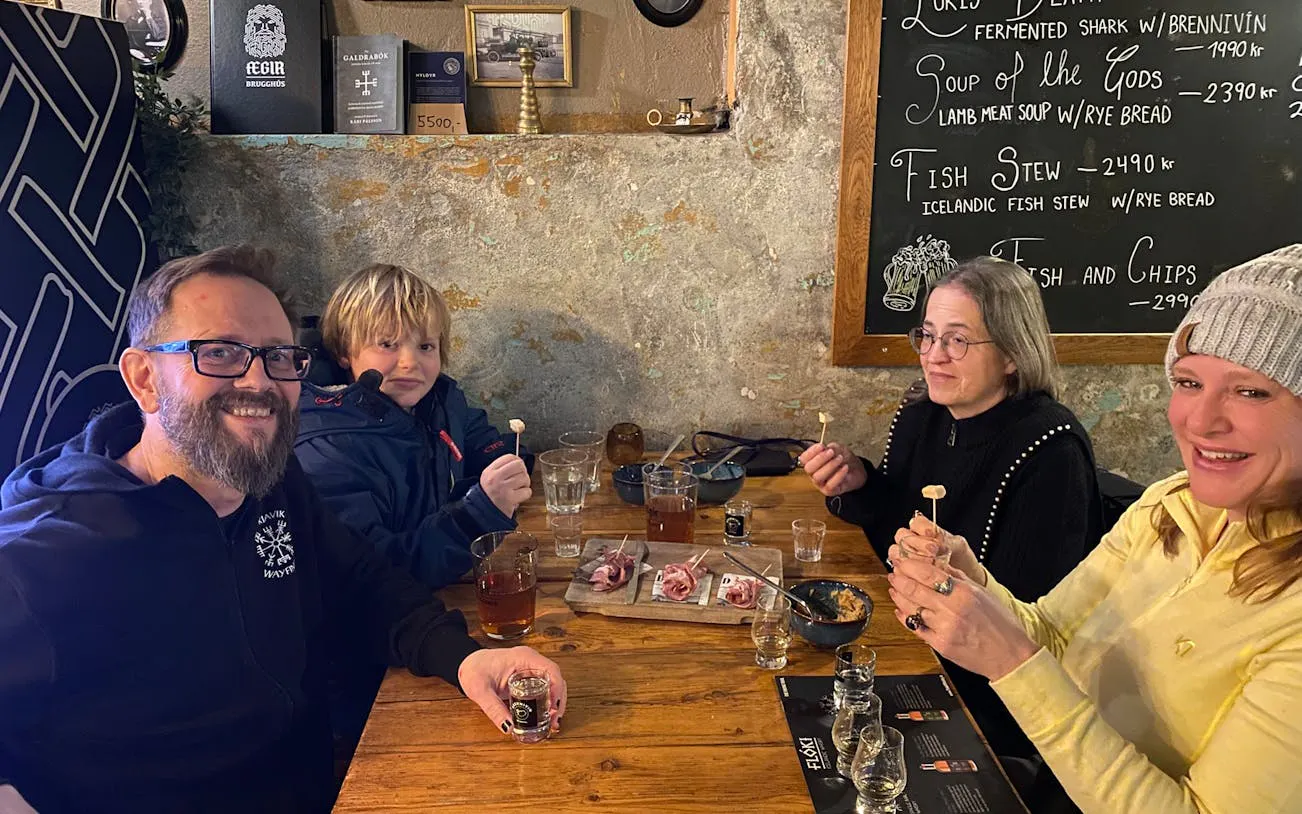 Tour group enjoying Icelandic food tasting in Reykjavik pub with local dishes and drinks.