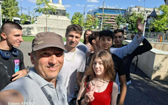 Group of people enjoying a sunny day near a monument in Bucharest during a self-guided city exploration game.