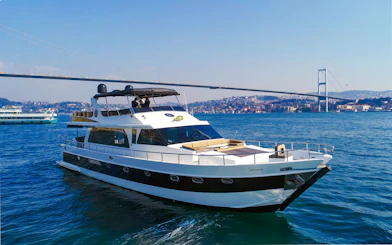 Luxury yacht cruising on the Bosphorus with Istanbul's skyline and bridge in the background.