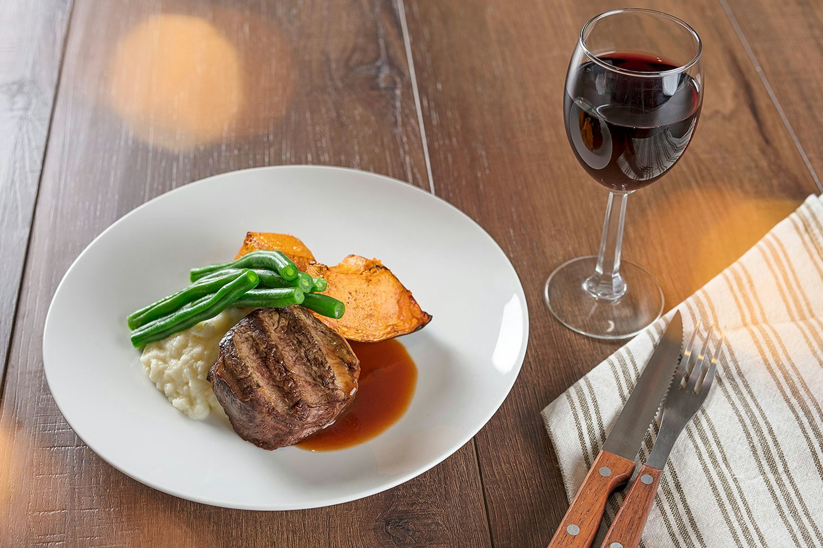 Steak dinner with green beans, sweet potato, and wine at Australian Outback Spectacular Heartland Show.