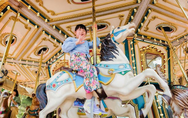 Child riding a carousel horse at Tokyo Summerland.