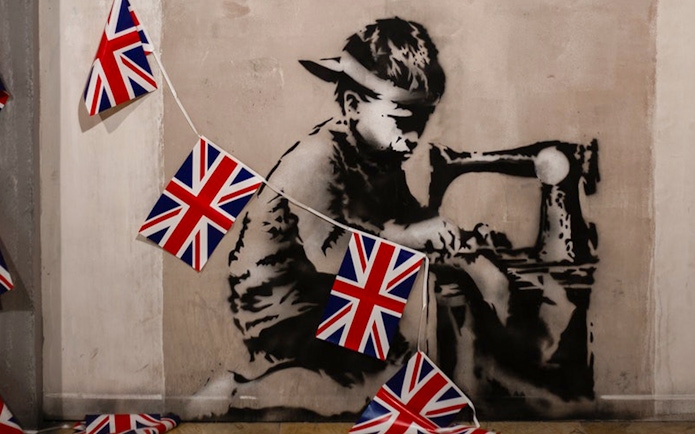 Child stencil art with sewing machine and UK flags at Banksy museum.