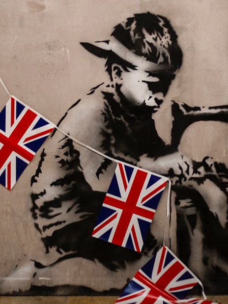 Child stencil art with sewing machine and UK flags at Banksy museum.