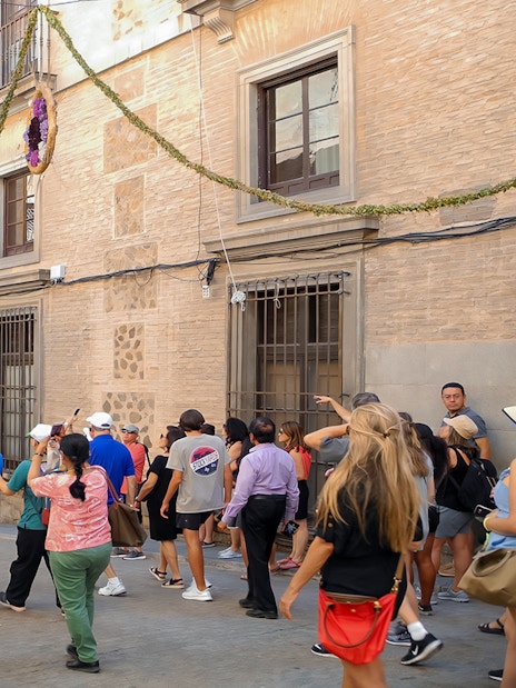 Tour group walking through decorated street in Toledo, Spain.
