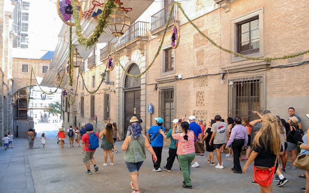 Tour group walking through decorated street in Toledo, Spain.