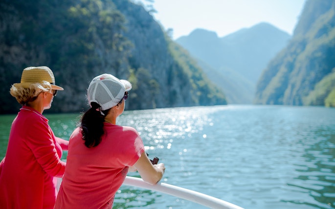 Tourists enjoying a boat ride with scenic views of Cinque Terre cliffs and water.