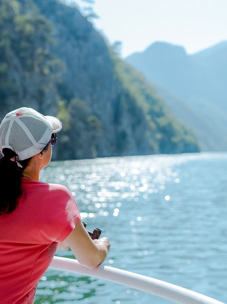 Tourists enjoying a boat ride with scenic views of Cinque Terre cliffs and water.