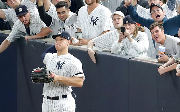 Baseball player catching a ball near fans at New York Yankees vs Washington Nationals game.