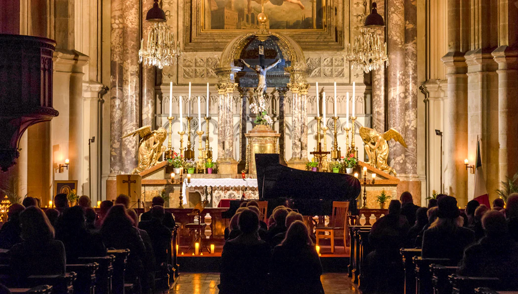 Classical concert audience at Minoritenkirche with grand piano and ornate altar.
