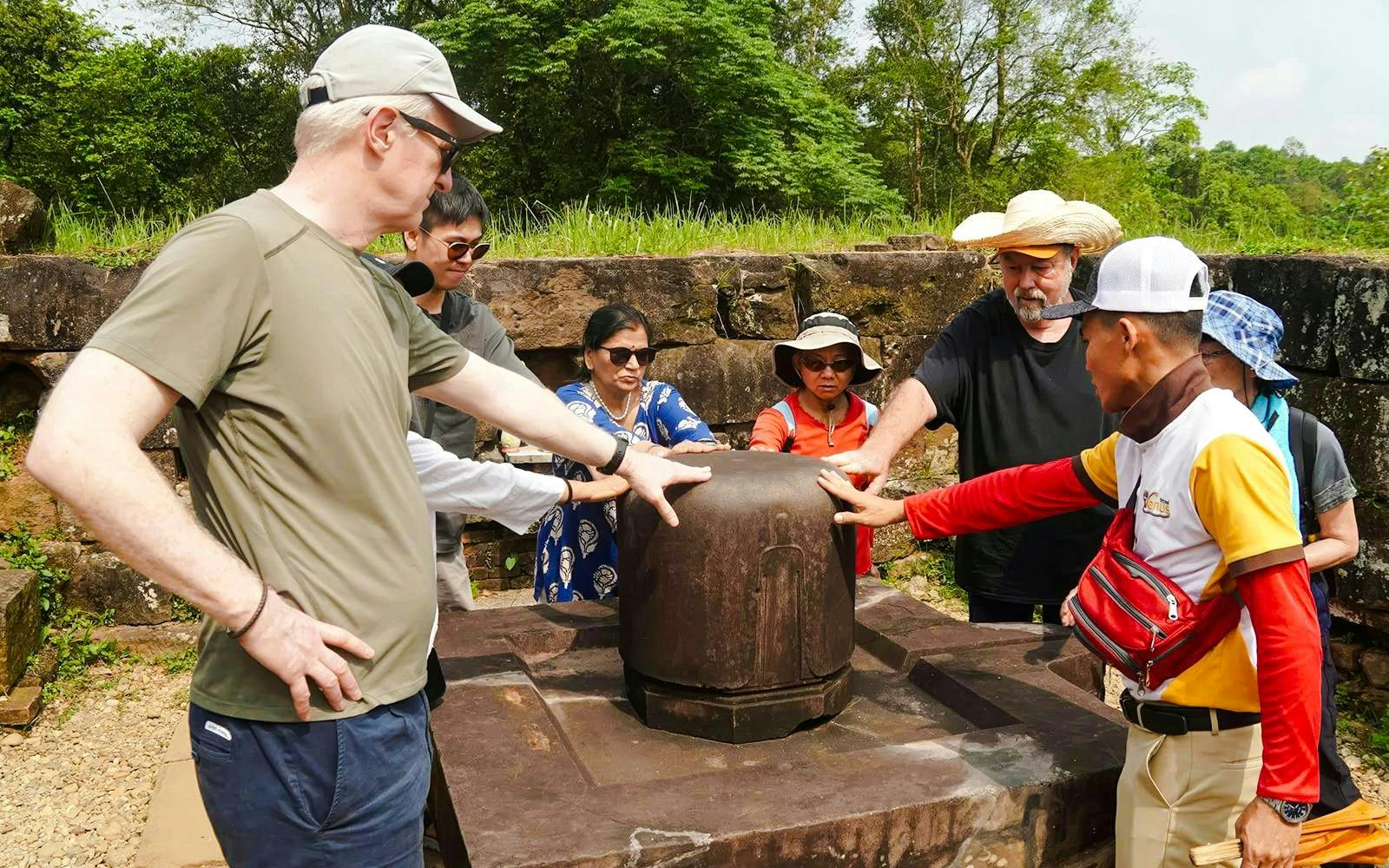 Tour group examining ancient artifact at My Son Sanctuary, Vietnam.