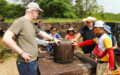 Tour group examining ancient artifact at My Son Sanctuary, Vietnam.